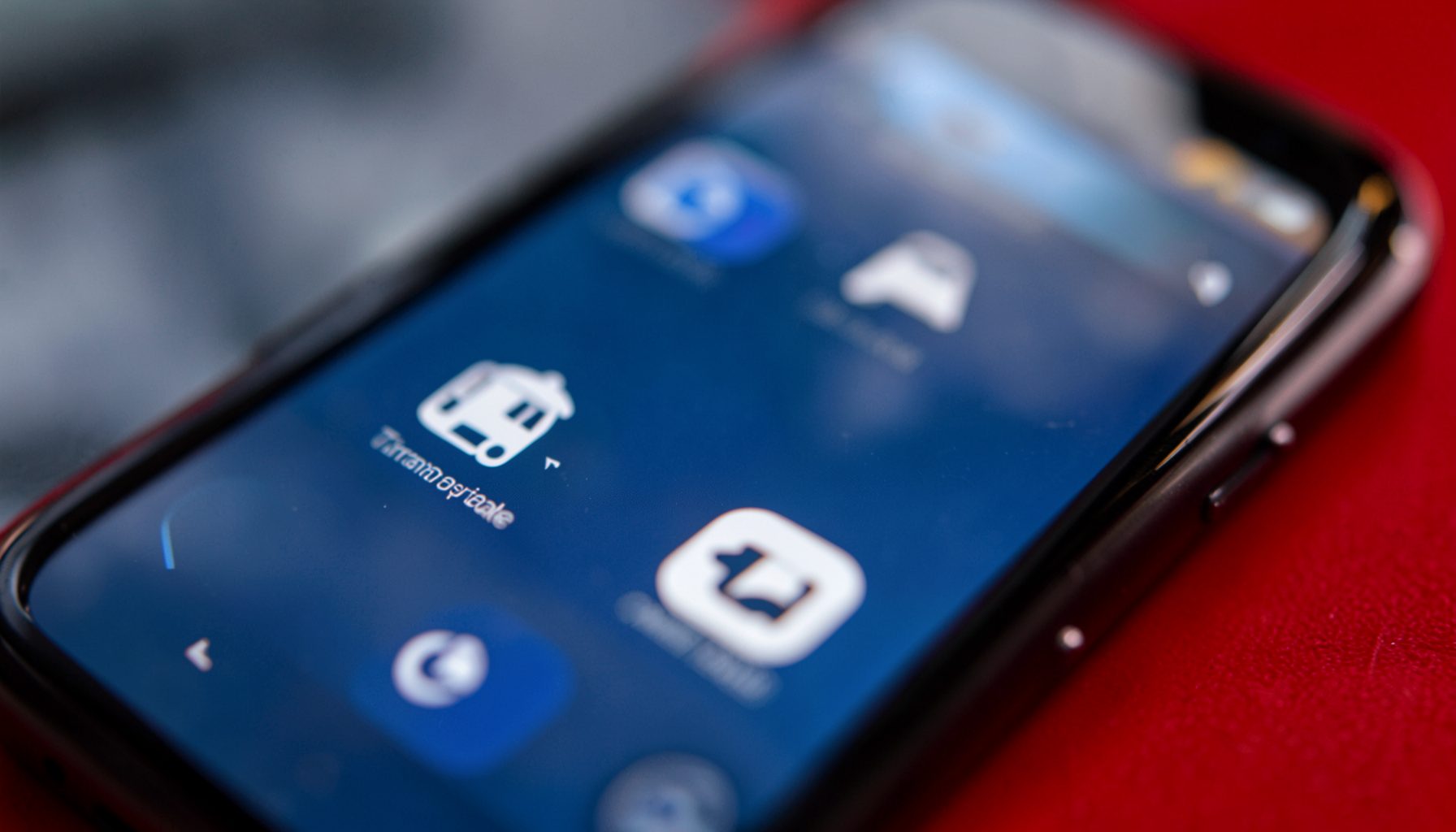 Layar smartphone menampilkan beberapa ikon aplikasi transportasi, dengan pantulan cahaya lembut pada kaca, warna dominan biru tua dan putih