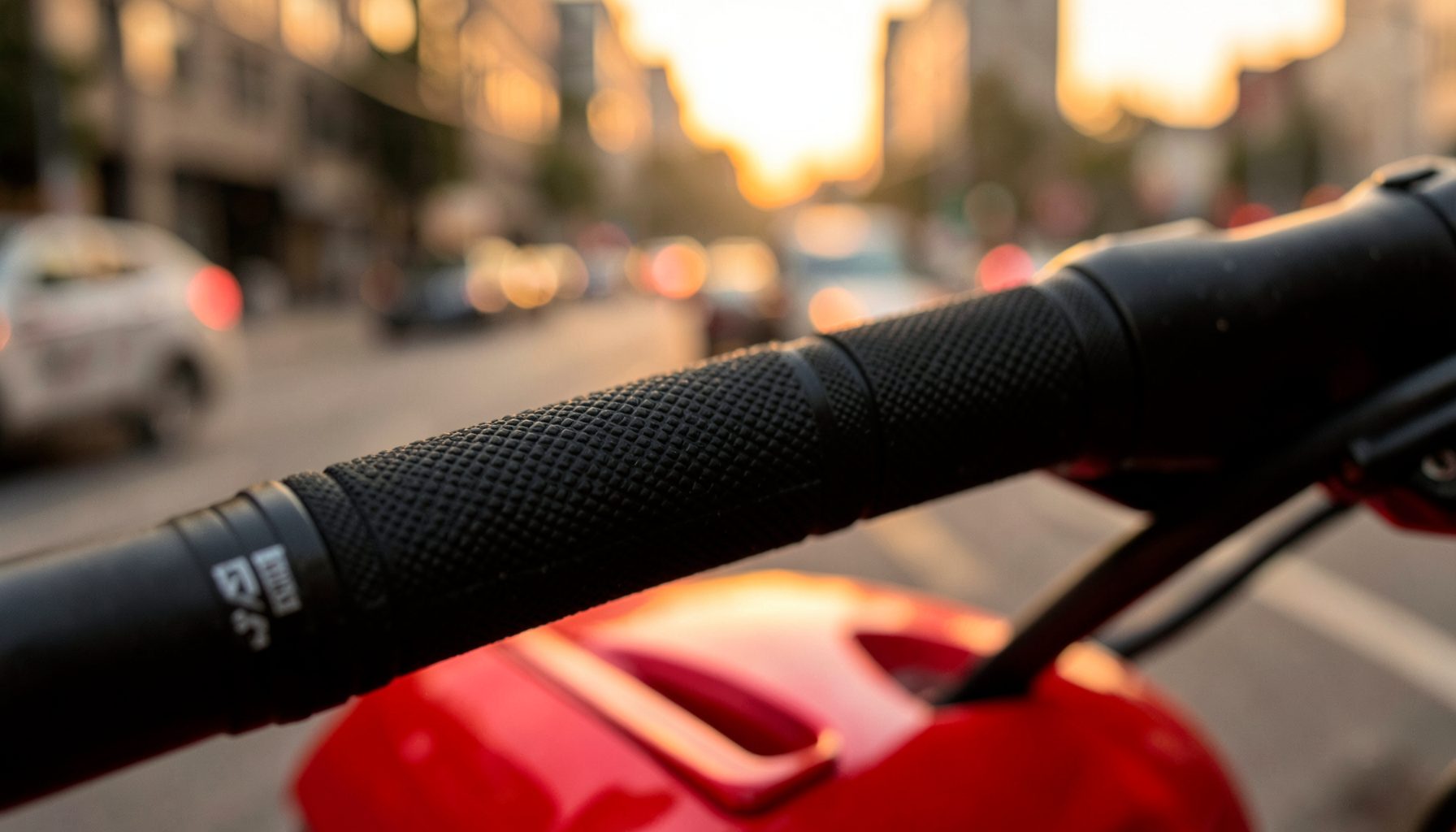 Close-up setang motor dengan grip karet hitam bertekstur, latar belakang buram jalanan kota saat senja, warna jingga keemasan